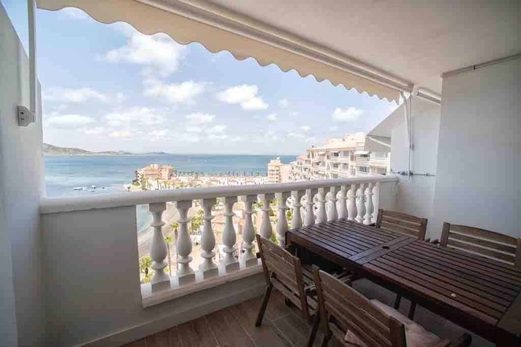 balcón con mesa de madera y vistas al océano en Renovated apartment in La Manga with great sunset, en La Manga del Mar Menor