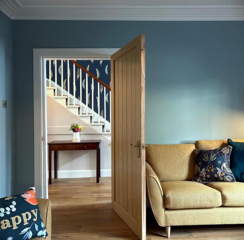 a living room with a couch and a staircase at The Fiddich Luxury Home in Craigellachie in Craigellachie