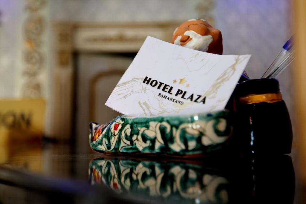 Hotel Plaza 777 في سمرقند: طاولة مع لافتة ساحة الفندق ومعجنات