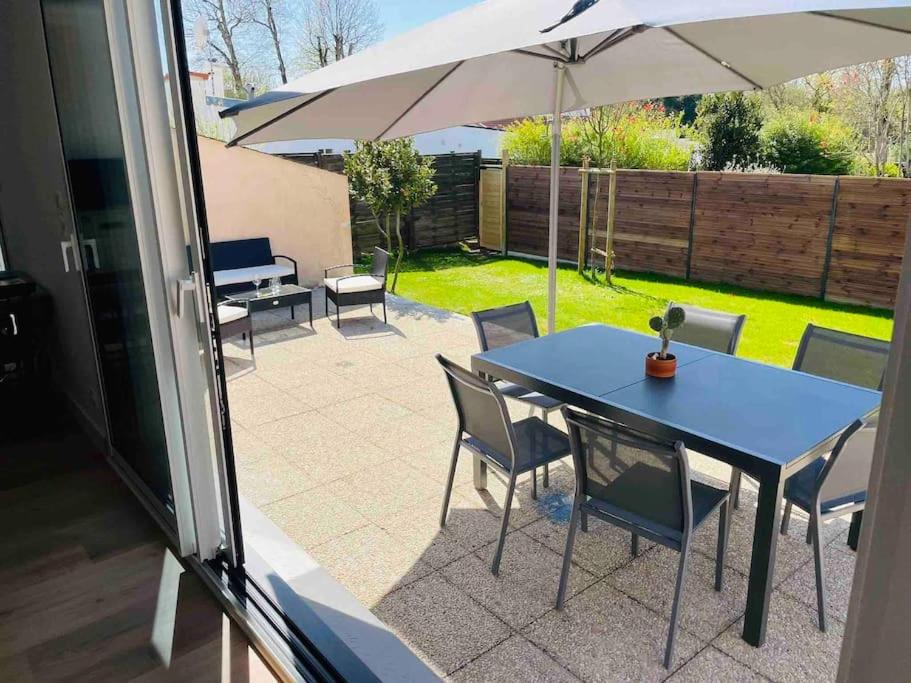 une table et des chaises bleues avec un parasol dans l'établissement Maison Pornichet -3 ch- Proche hippodrome, plages, à Pornichet