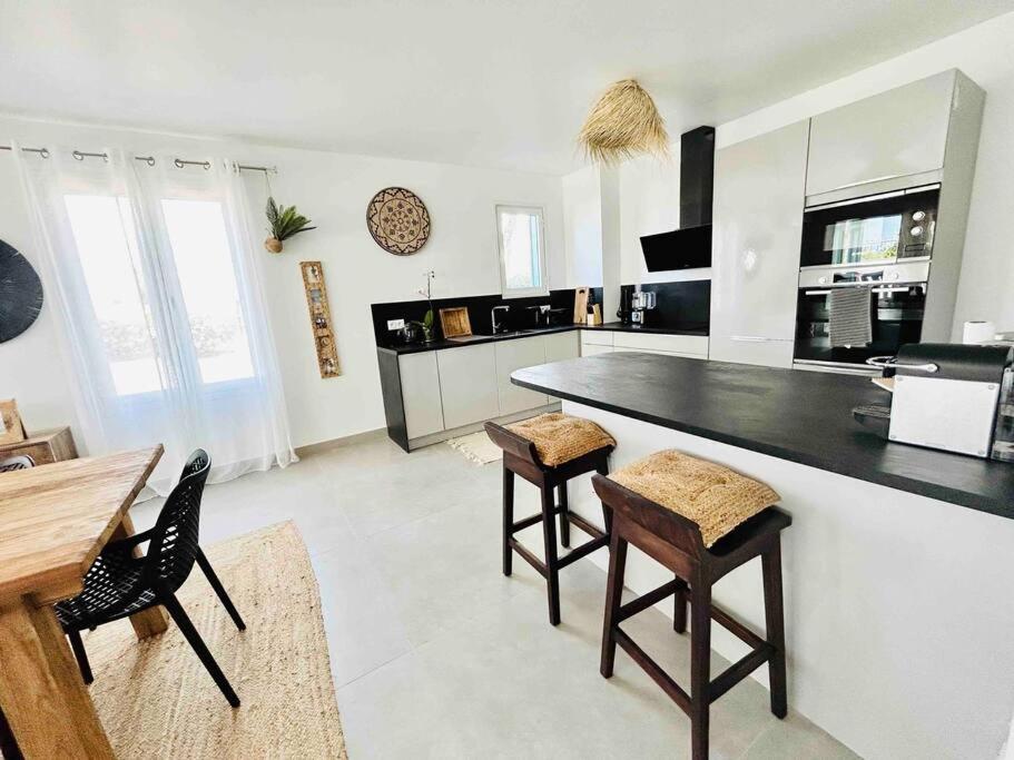 a kitchen with a large black counter and chairs at 120 m2 bord de mer in Saint Martin