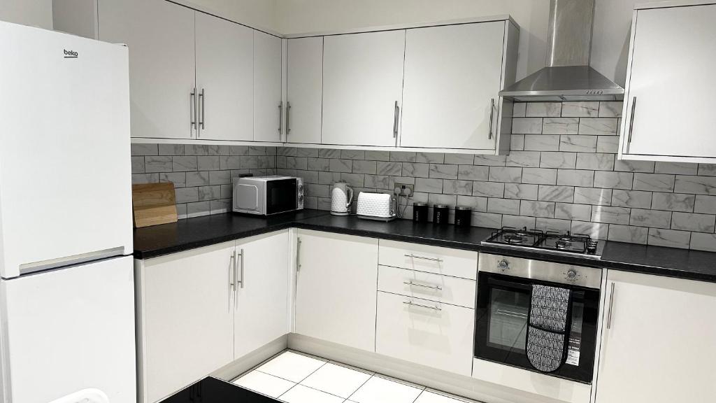 uma cozinha branca com armários brancos e um micro-ondas em Comfortable Modern Bedroom Space with Ensuite near Bramall Lane Stadium and RHH em Sheffield