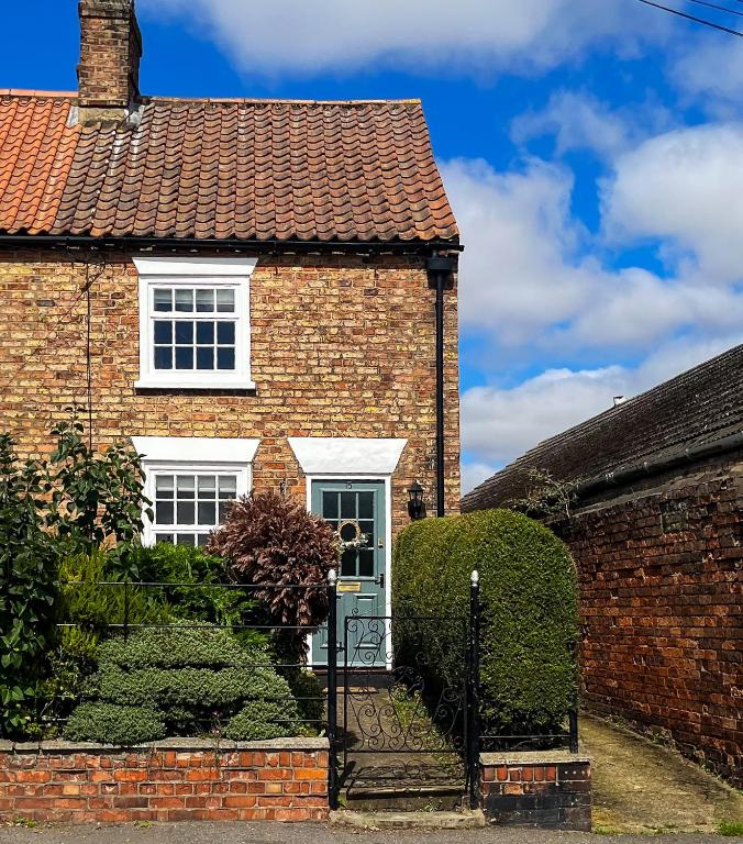 a brick house with white windows and a gate at Auctioneers Cottage in Louth