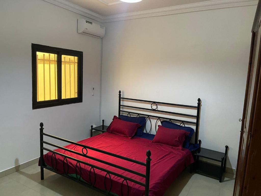 Schlafzimmer mit einem Bett mit roter Bettwäsche und einem Fenster in der Unterkunft Villa sokhna ndeye mbacke in Dakar