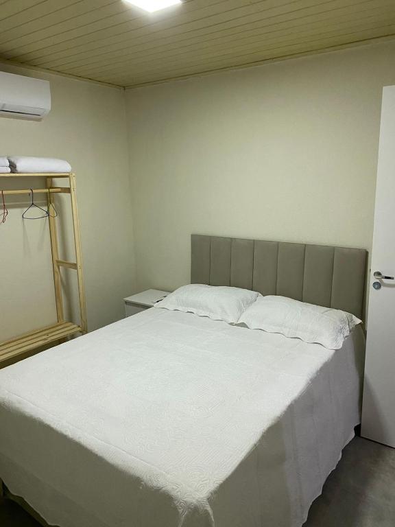 a bedroom with a large bed with white sheets at Hospedagens Express I in Chapada dos Guimarães