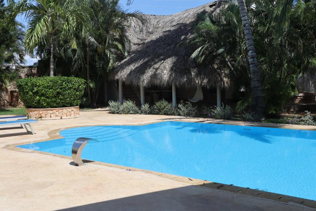 a swimming pool in a resort with a thatch roof at Villa SOL in Cumayasa Kilómetros 4 1/2