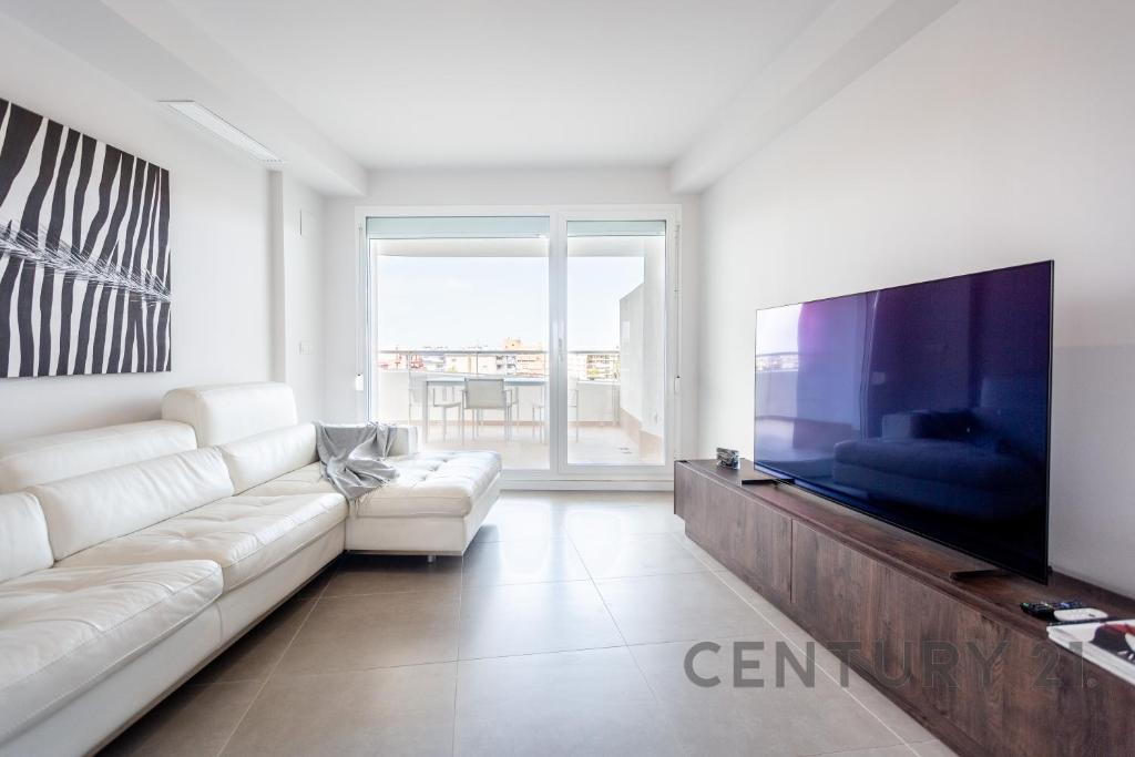 a living room with a white couch and a large tv at Apartamento de lujo con 2 habitaciones en Canet d'en Berenguer in Canet de Berenguer