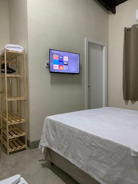a bedroom with a bed and a flat screen tv on the wall at Hospedagens Express II in Chapada dos Guimarães