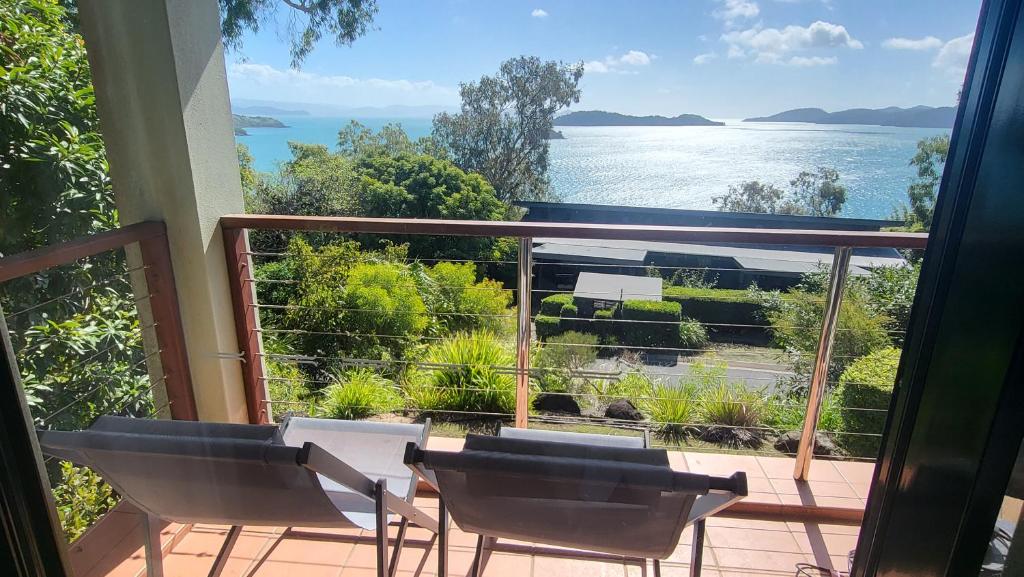 a balcony with chairs and a view of the water at Luxury Couples Retreat Hamilton Island and golf buggy - Renovated August 2023 in Hamilton Island