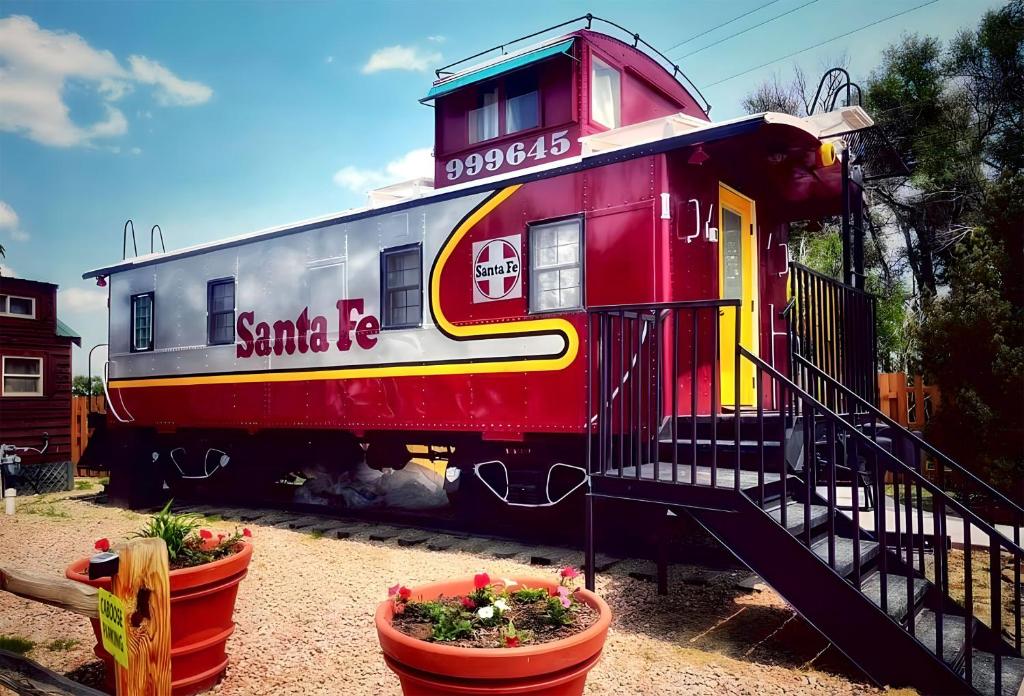 un vagón de tren rojo sentado al lado de algunas plantas en La Junta Colorado Cabins, en La Junta