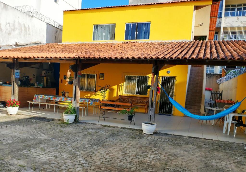 uma casa amarela com uma rede em frente em Casa Amarela Hostel em Guarapari