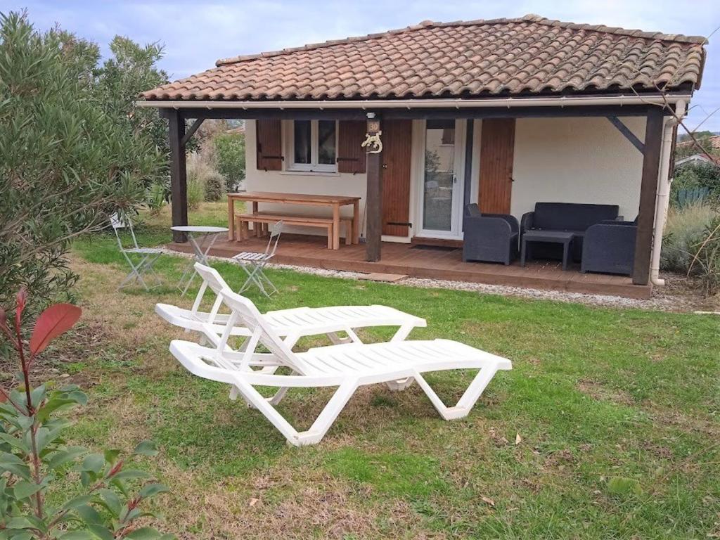 Deux chaises blanches assises dans l'herbe devant une maison dans l'établissement Maison 2 chambres avec piscine, tennis, et plus - idéal pour 4 personnes à Vallon-Pont-d'Arc - FR-1-382-179, à Vallon-Pont-dʼArc
