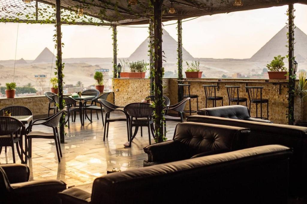 ein Restaurant mit Stühlen und Tischen mit Pyramiden im Hintergrund in der Unterkunft King Khafren View INN in Kairo