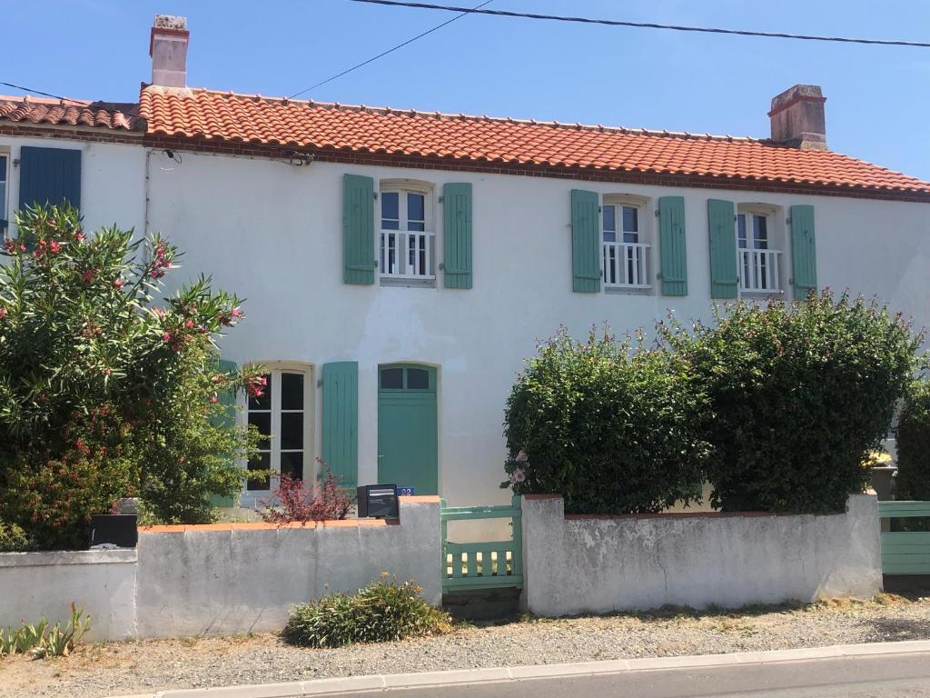 a white house with green shutters on a street at Grand-Pré in Noirmoutier-en-l'lle