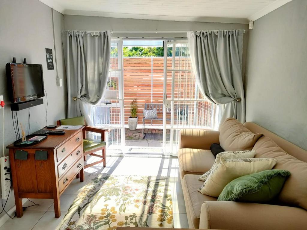 a living room with a couch and a sliding glass door at Adorable Garden Cottage In The Heart Of Pe in Lorraine