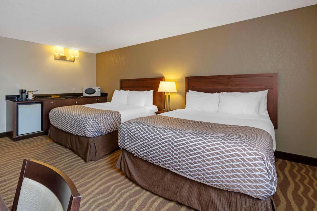 a hotel room with two beds and a desk at Best Western High Road Inn in Edson