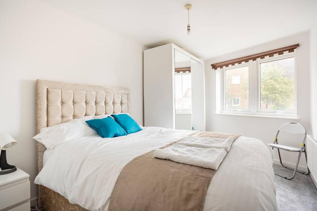 a white bedroom with a large bed with blue pillows at The Dartford Lodge in Kent