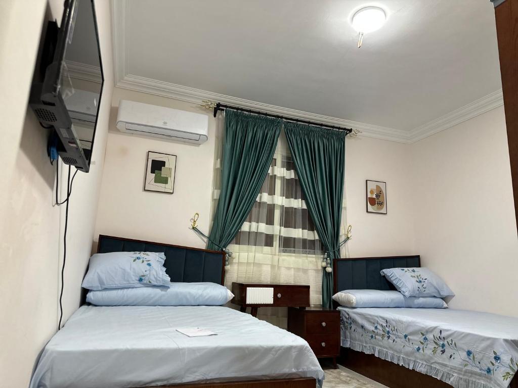a room with two beds and a television and a window at Two million hotel 5 in 6th Of October