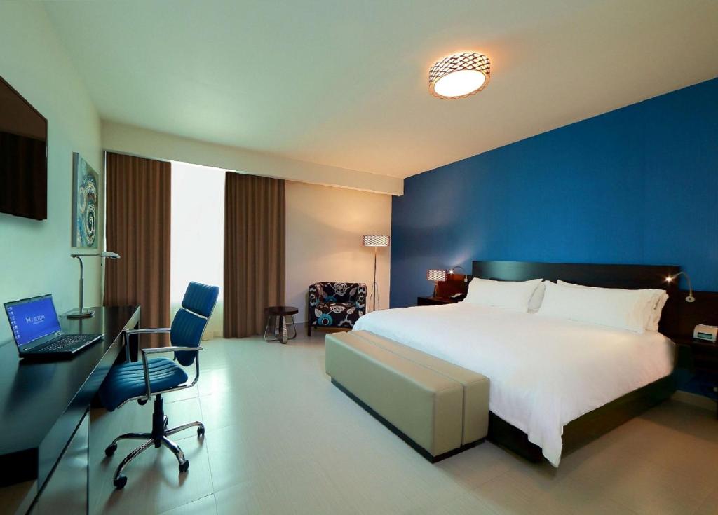 a bedroom with a bed and a desk with a laptop at Hampton by Hilton Panama in Panama City