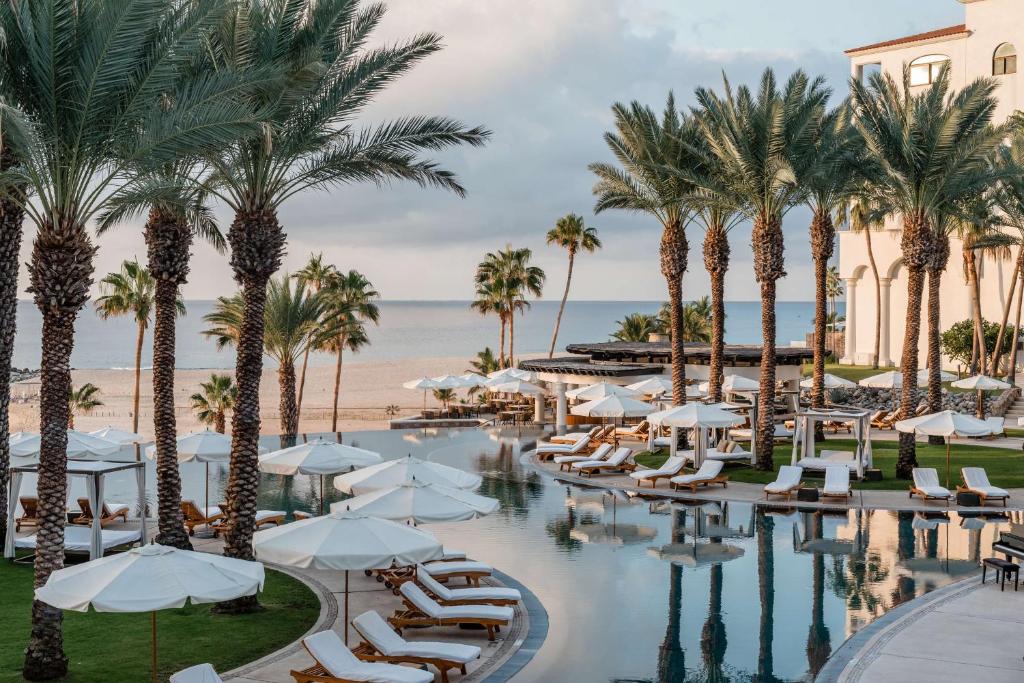 a hotel pool with chairs and palm trees at Hilton Los Cabos in San José del Cabo