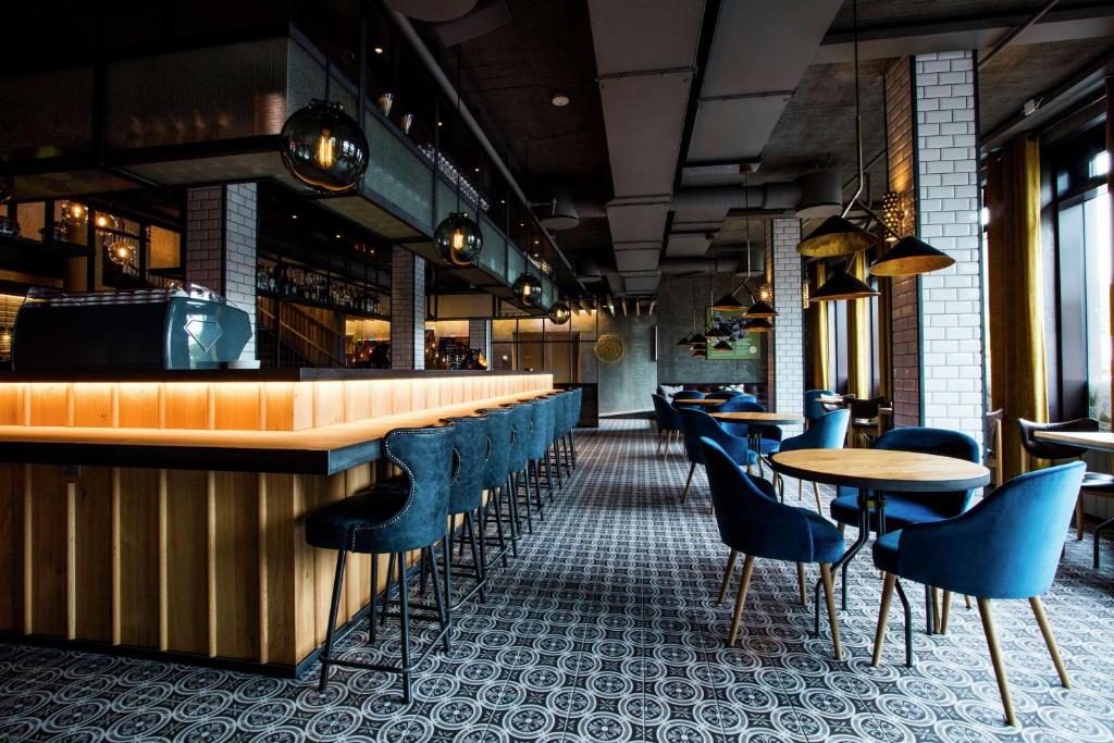 a bar with blue chairs and tables in a restaurant at Canopy by Hilton Reykjavik City Centre in Reykjavík