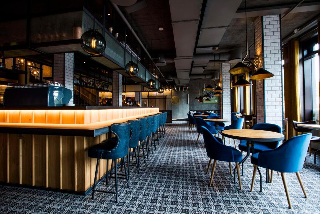 a bar with blue chairs and tables in a restaurant at Canopy by Hilton Reykjavik City Centre in Reykjavík