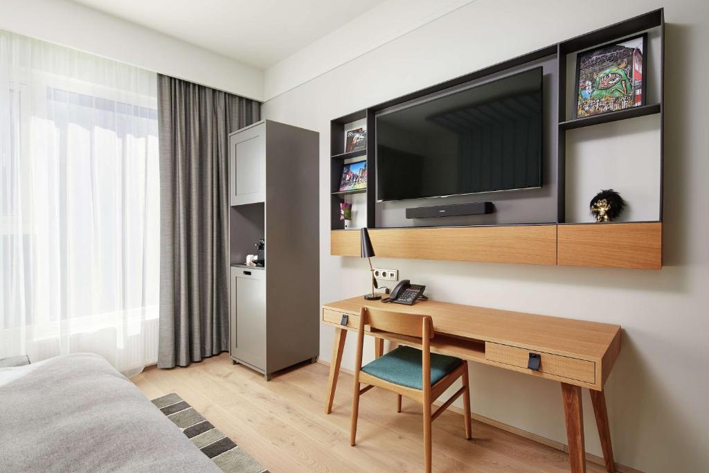 a hotel room with a desk with a television on a wall at Canopy by Hilton Reykjavik City Centre in Reykjavík