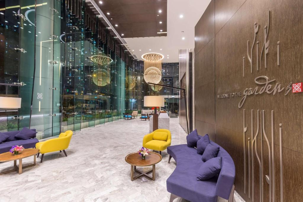 a lobby with purple couches and yellow chairs at Hilton Garden Inn Hong Kong Mongkok in Hong Kong