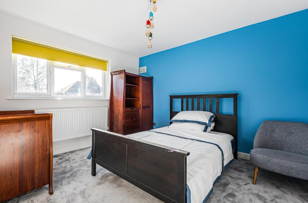 a bedroom with a bed and a chair at HARTFORDE HOUSE in Borehamwood