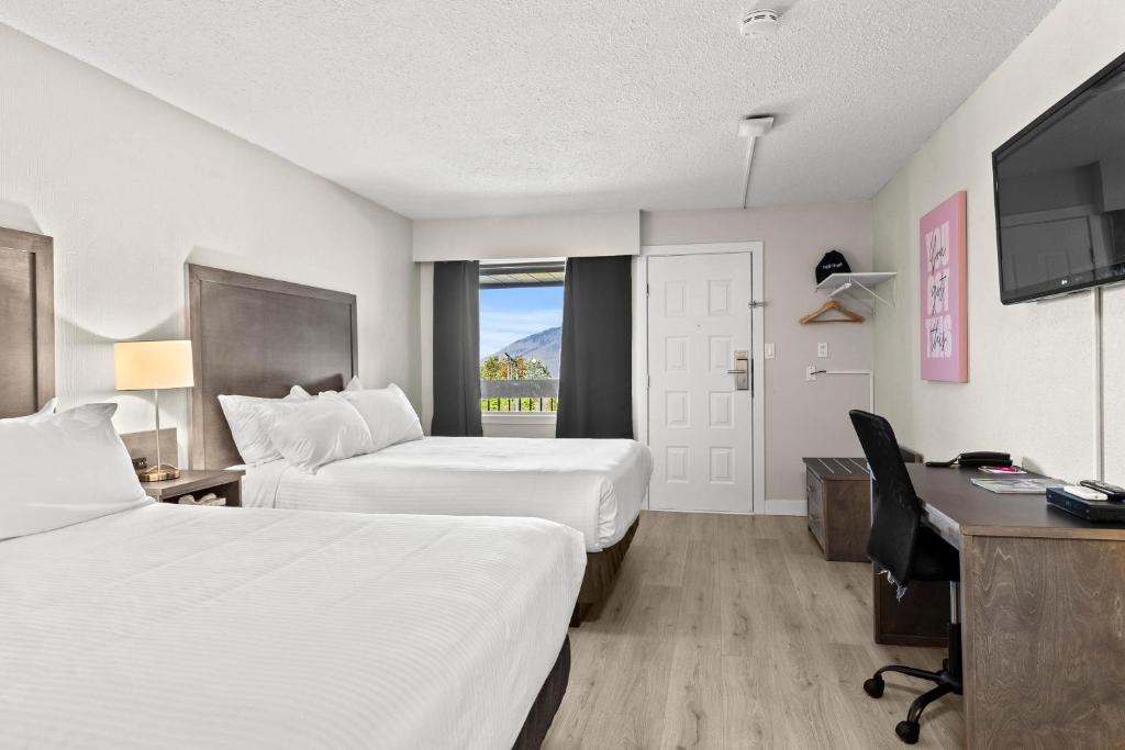 a hotel room with two beds and a desk at The Vista Inn in Kamloops