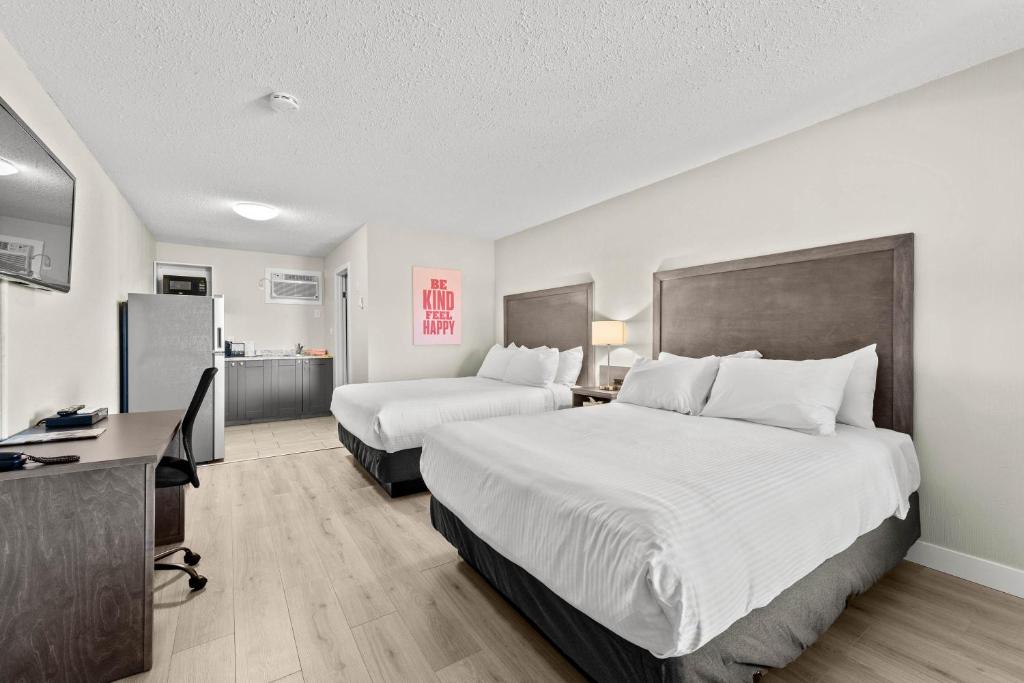 a hotel room with two beds and a desk at The Vista Inn in Kamloops