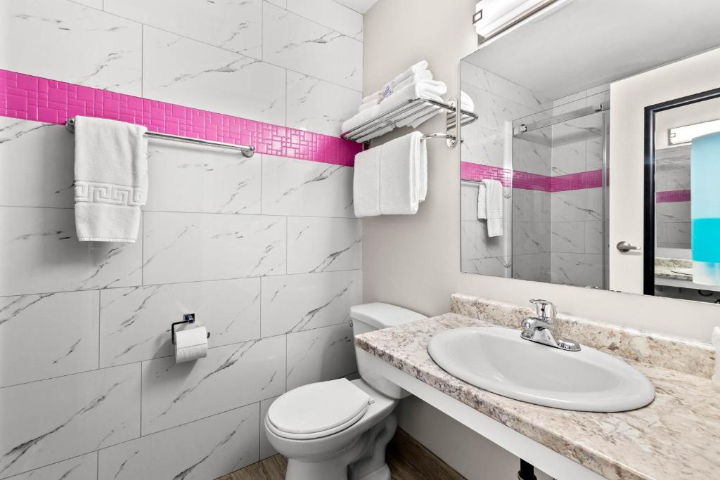 a white bathroom with a sink and a toilet at The Vista Inn in Kamloops