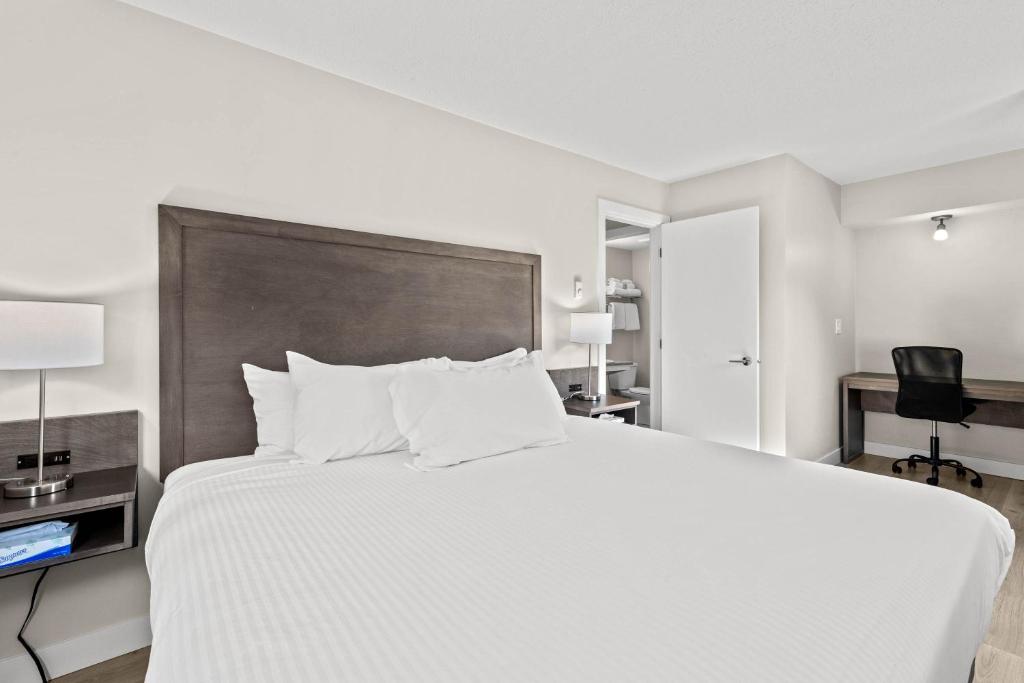 a bedroom with a large white bed and a desk at The Vista Inn in Kamloops