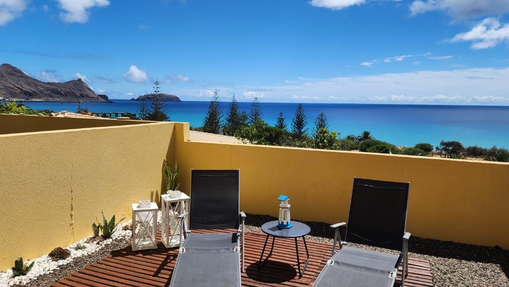 a patio with two chairs and a table and the ocean at Thelighthouse Porto Santo in Porto Santo