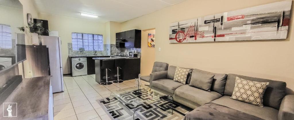 a living room with a couch and a kitchen at Banbury Estate luxury apartment in Johannesburg