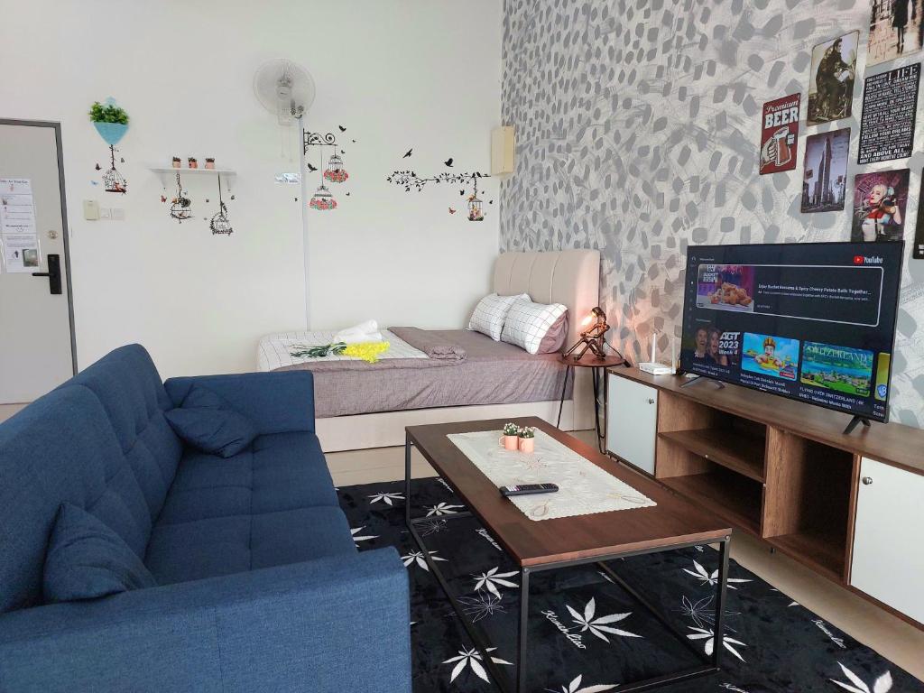 ein Wohnzimmer mit einem blauen Sofa und einem Bett in der Unterkunft Manhattan Mount Austin Dekasa Homestay in Johor Bahru