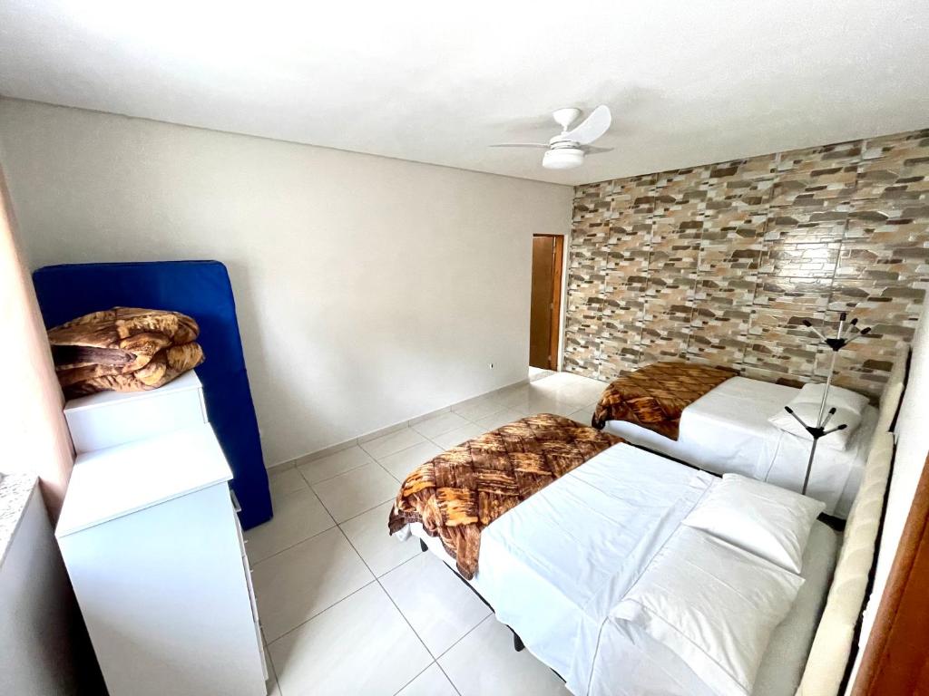 a bedroom with two beds and a stone wall at Recanto da Ivete in São Sebastião