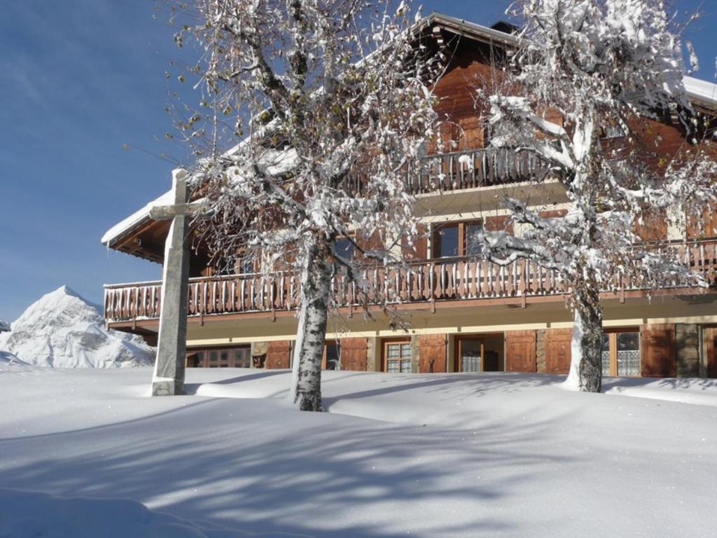 a building with a balcony and two trees in the snow at Appartement 6 pers, 3 ch, centre village, avec WIFI et poêle à granules - FR-1-733-85 in Crest-Voland
