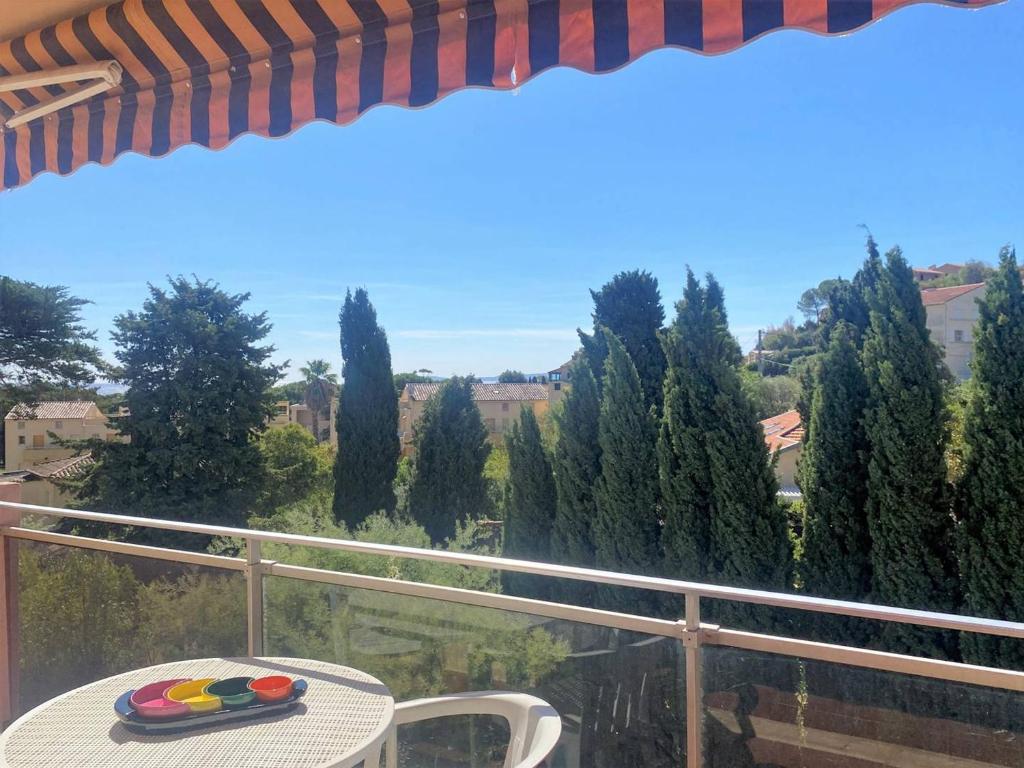 - une table sur un balcon avec vue sur les arbres dans l'établissement Appartement calme, 4 couchages, proche plage et commerces, terrasse exposée sud, parking privatif - FR-1-251-508, au Lavandou