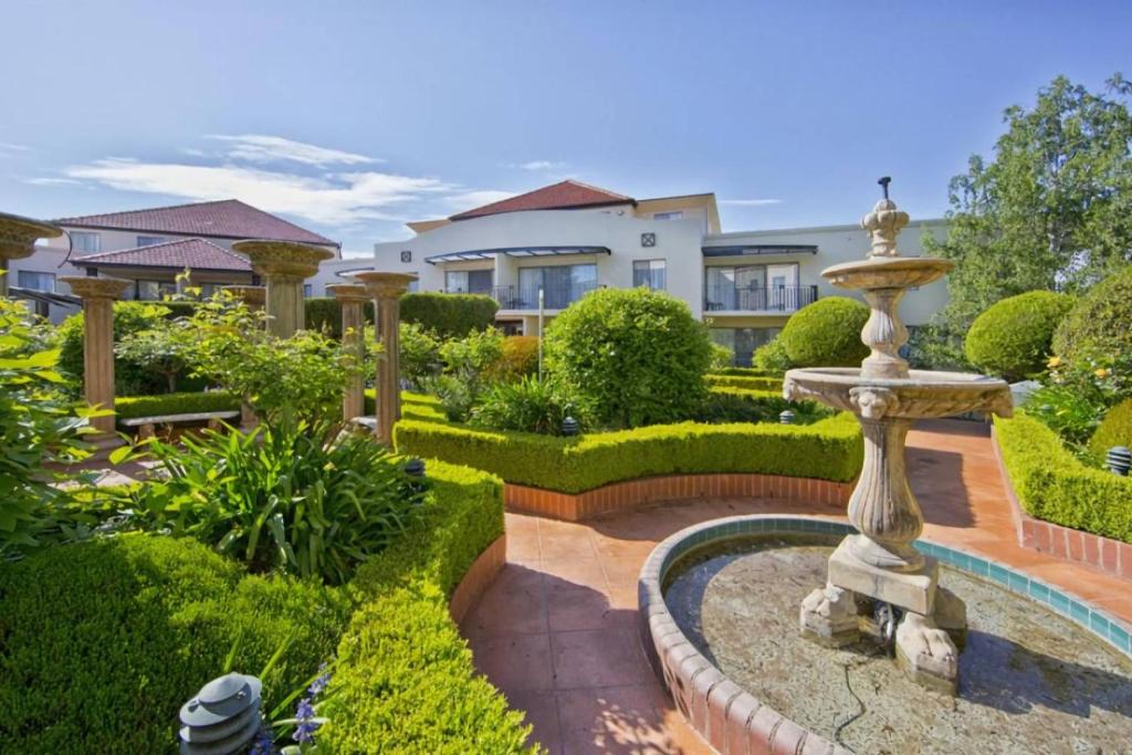 a garden with a fountain in front of a house at Griffin Apartments Kingston ACT in Canberra