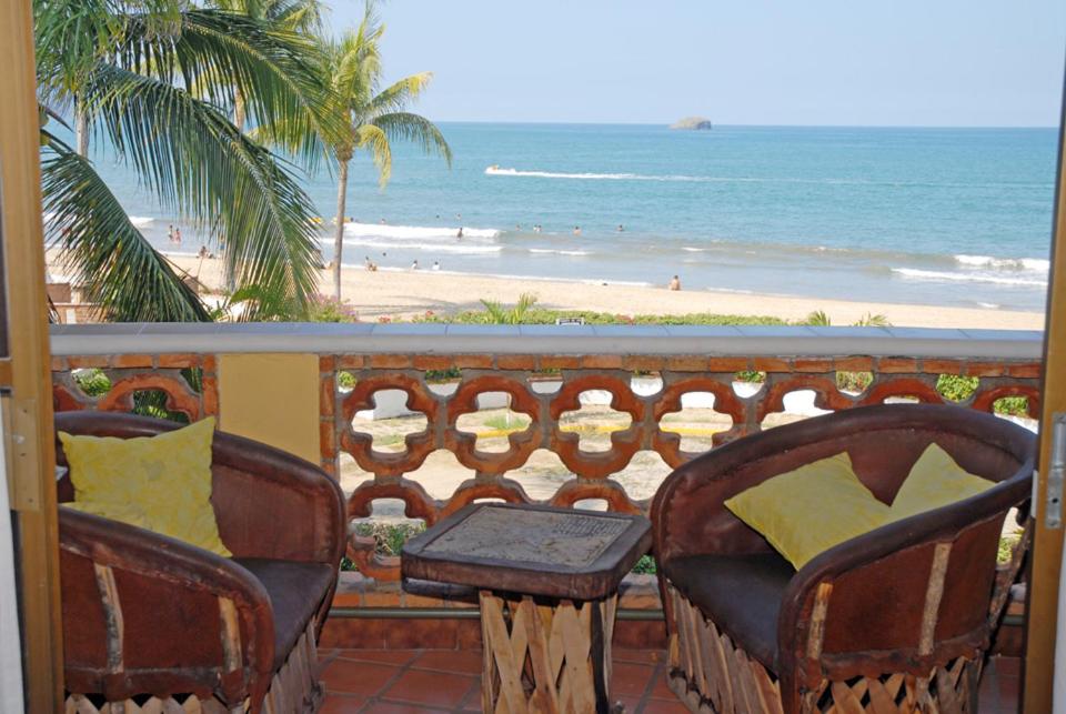 a balcony with chairs and a table and the beach at Villa Corona del Mar in Rincon de Guayabitos