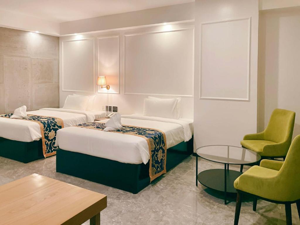 Habitación de hotel con 2 camas, mesa y sillas en Hevea Hotel & Resort, en Ángeles