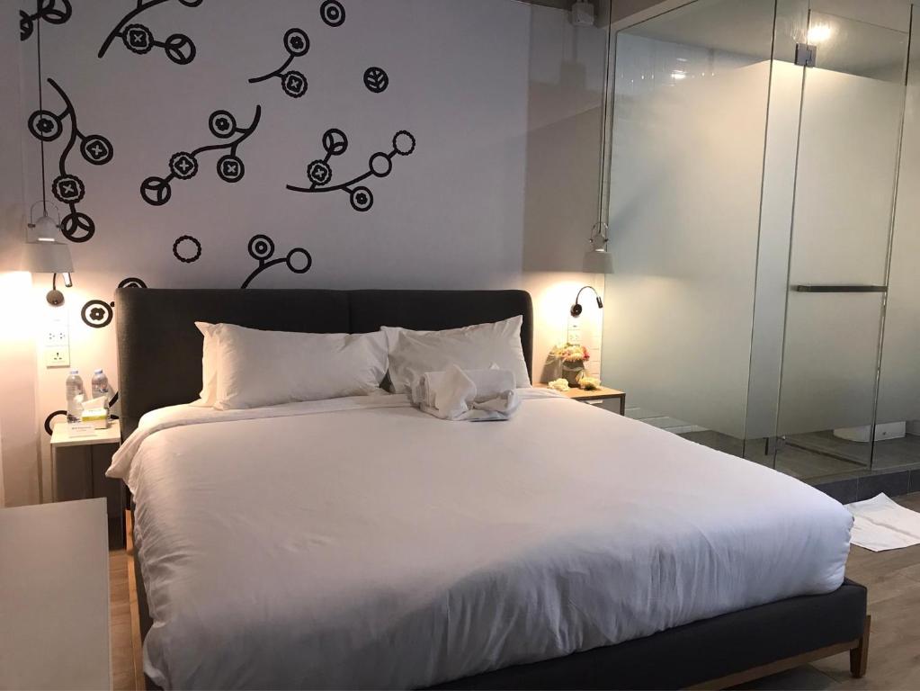 バンコクにあるベッドスプレッド ホステルのベッドルーム(白いベッド、黒いヘッドボード付)