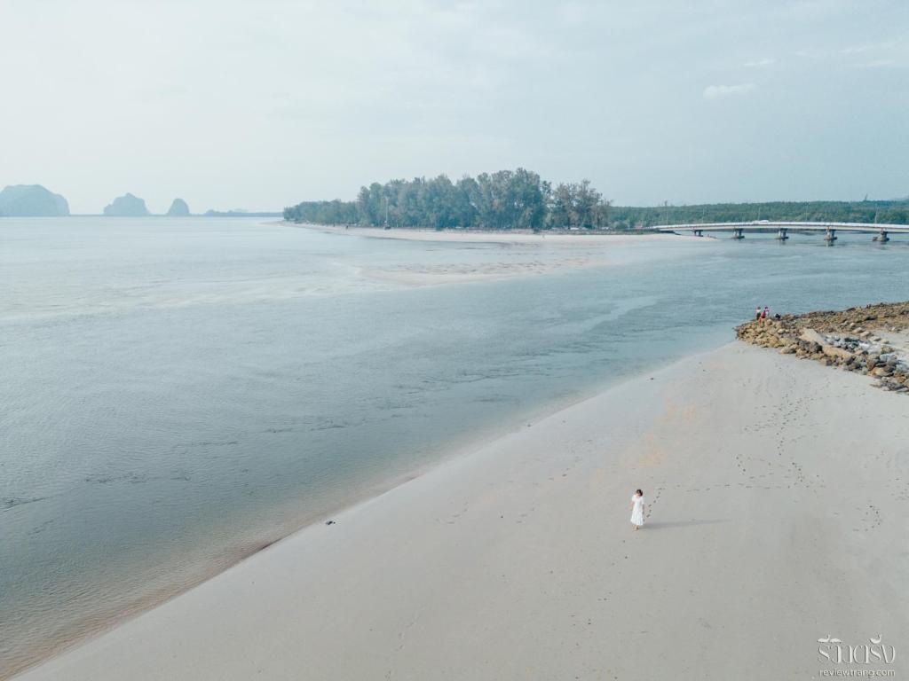 a person standing on a beach near the water at Dugong Village-Green Hotel in Pak Meng