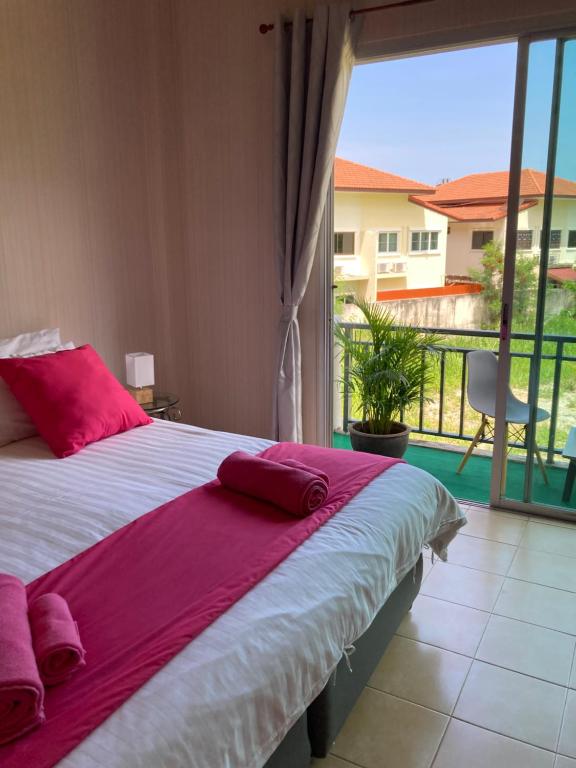 a bedroom with a bed with pink pillows and a balcony at Guest house Helene in Kata Beach
