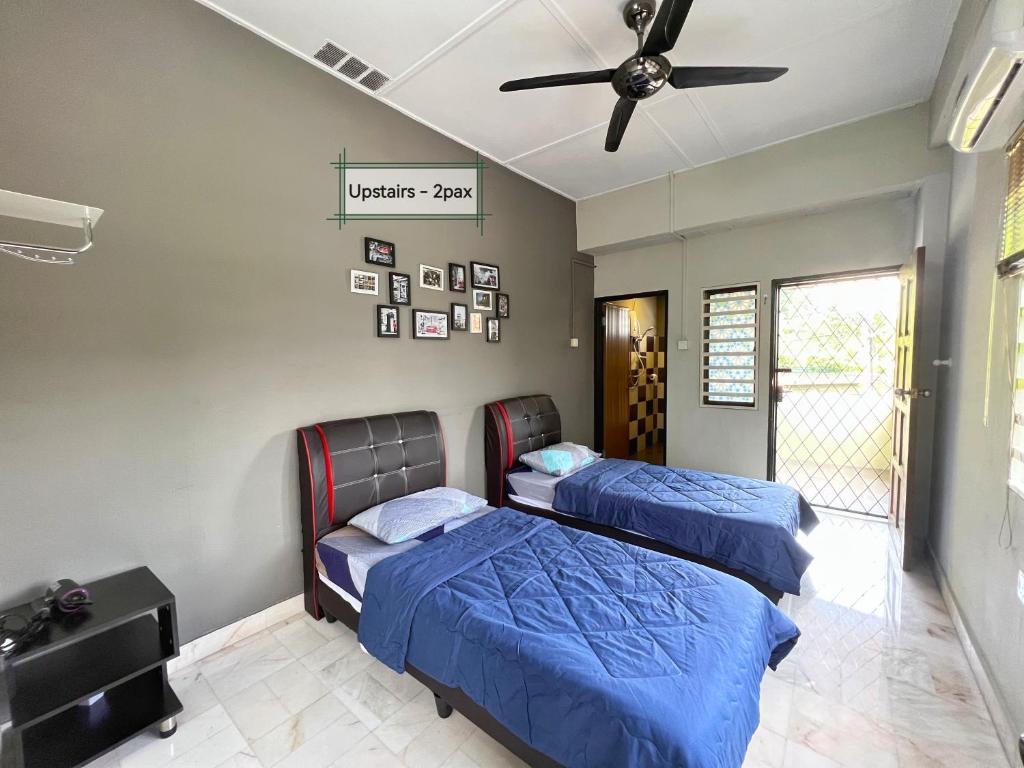 een slaapkamer met 2 bedden en een plafondventilator bij G East Ipoh Garden Guesthouse in Ipoh