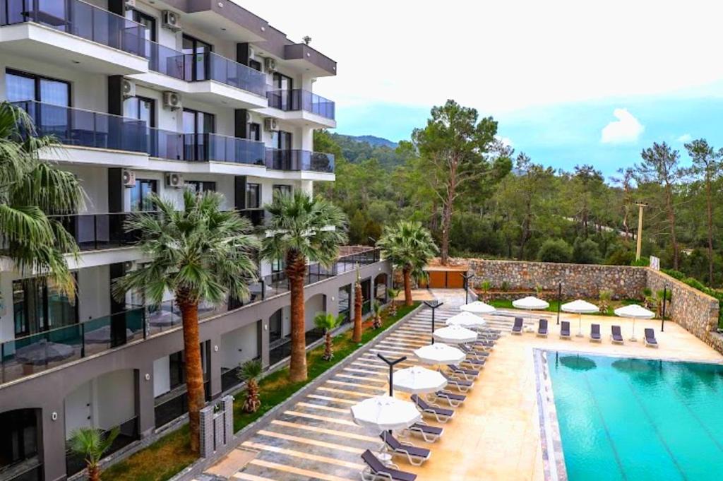 an apartment building with a swimming pool and lounge chairs at RiLen-House in Akbük