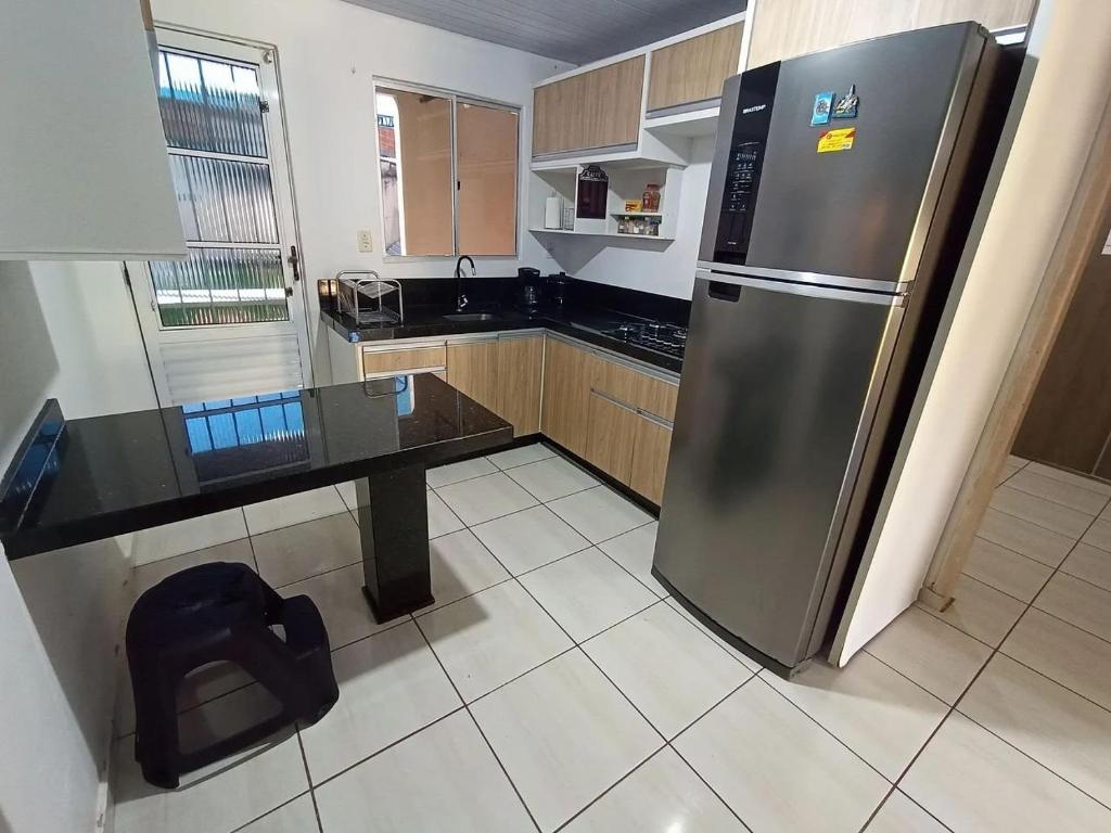Il comprend une cuisine équipée d'un réfrigérateur en acier inoxydable et d'un comptoir. dans l'établissement Casa Super Econômica com Café, à Foz do Iguaçu