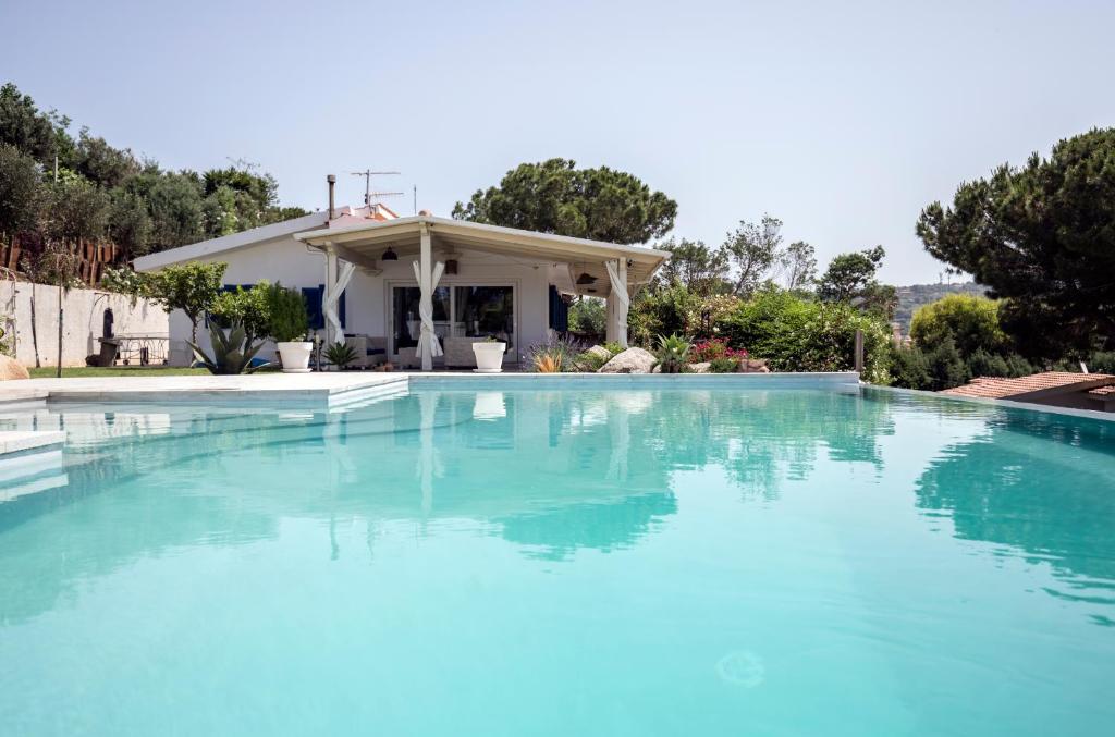 una piscina con acqua blu di fronte a una casa di Villa Michaela con piscina privata e vista mare a Capo Vaticano