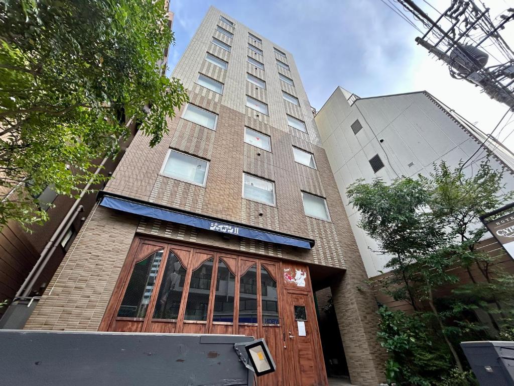 un edificio alto con una porta di legno di fronte di Cypressinn Tokyo a Tokyo